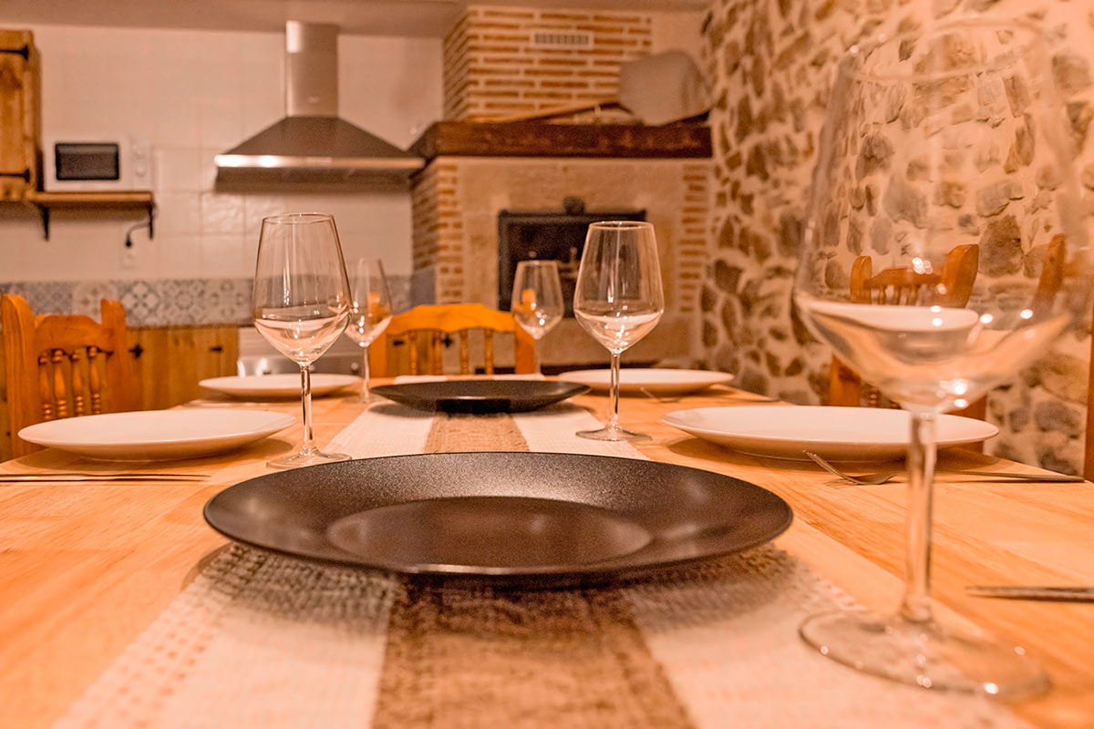 Mesa preparada con platos y copas en un comedor.