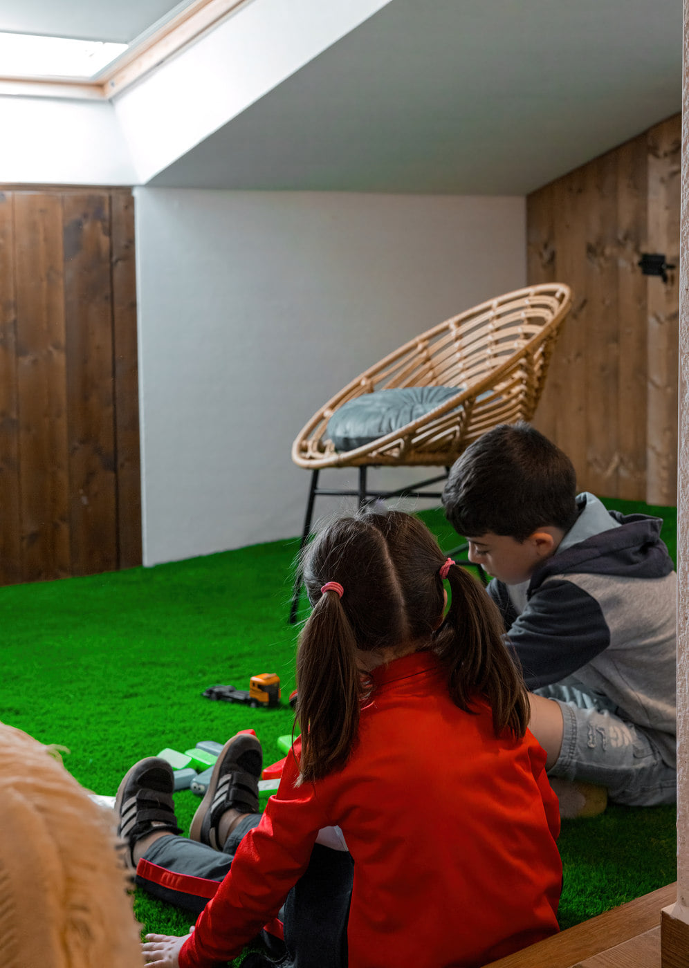 Niños jugando en una sala con césped artificial.
