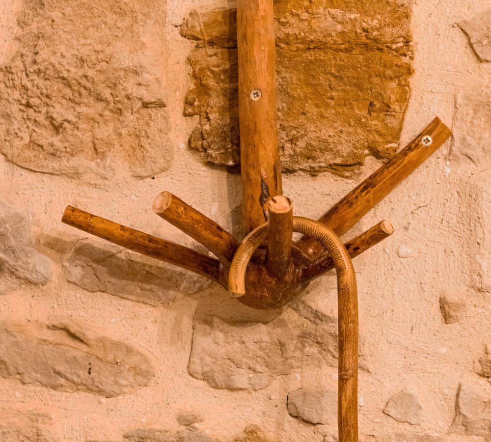 Perchero de madera en una pared de piedra.