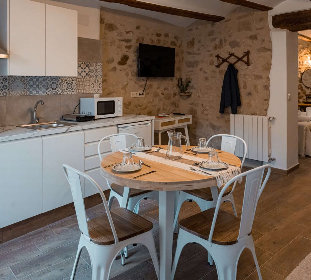 Cocina moderna con mesa y sillas blancas.