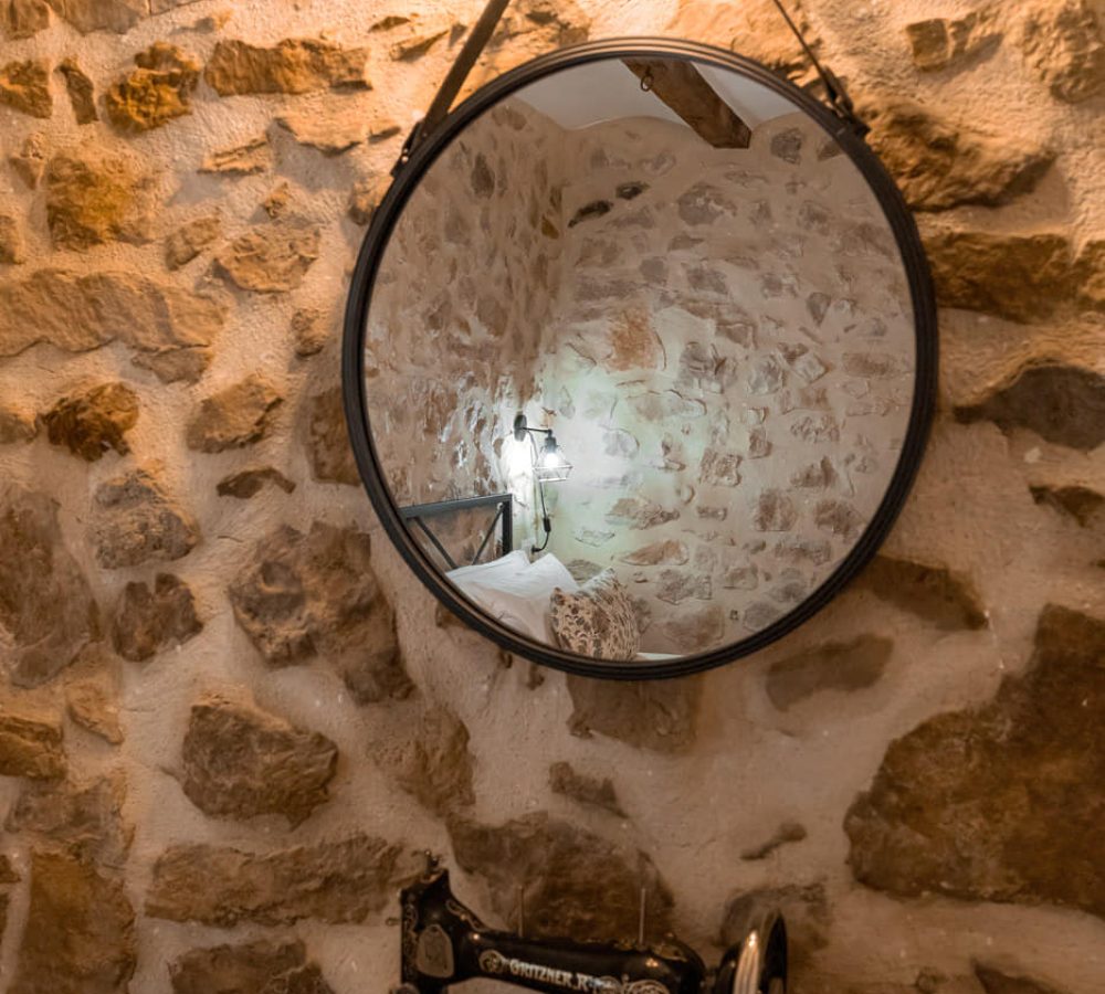 Espejo circular sobre pared de piedra.