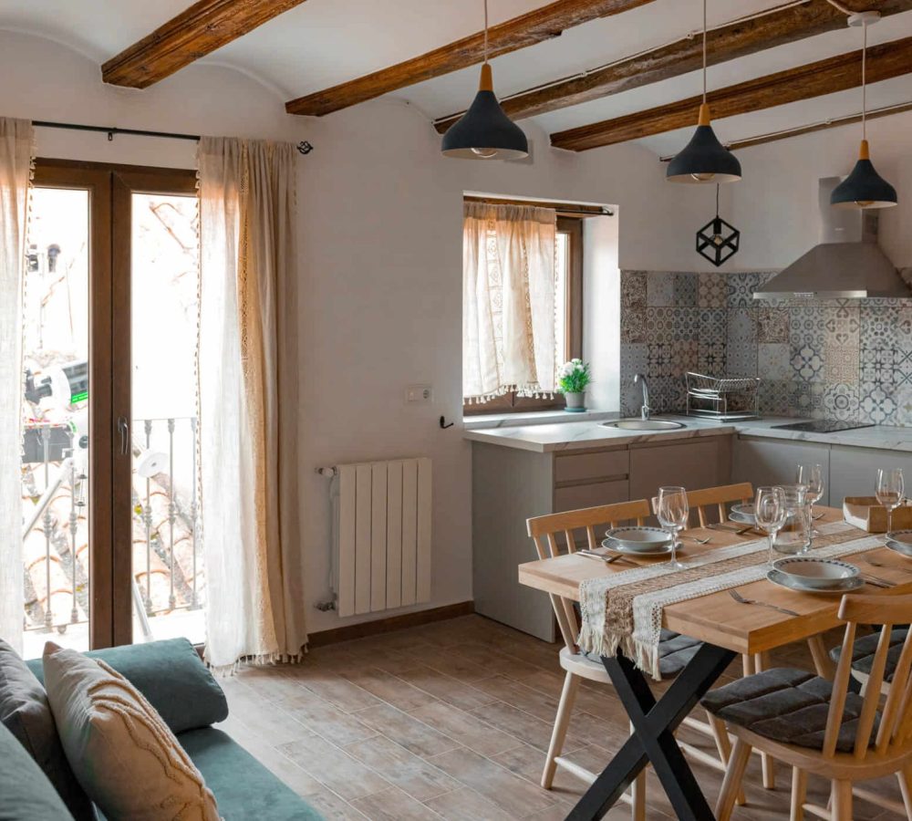 Cocina moderna con mesa y ventanas luminosas.