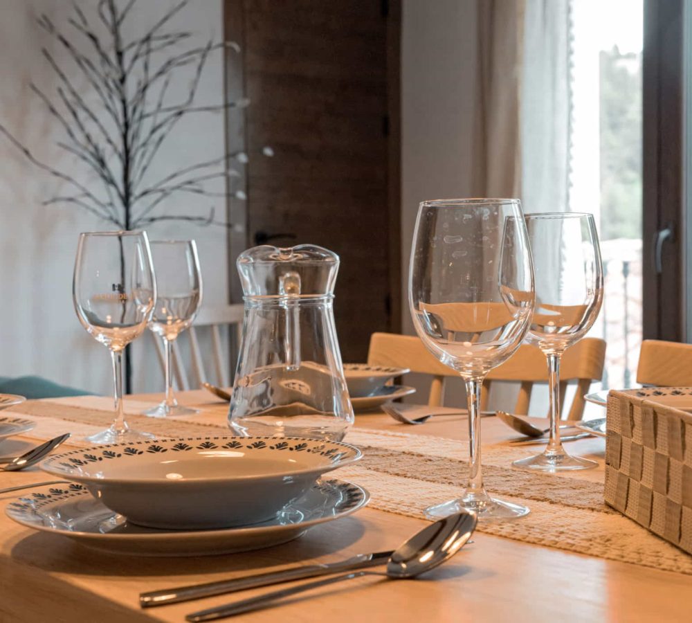 Mesa elegantemente decorada con vajilla y copas.