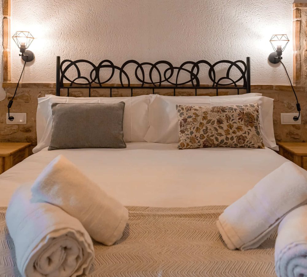 Cama acogedora con almohadas y toallas decorativas, apartamentos en Linares de Mora