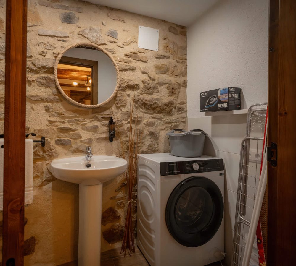 Lavandería con lavadora y lavabo en piedra.