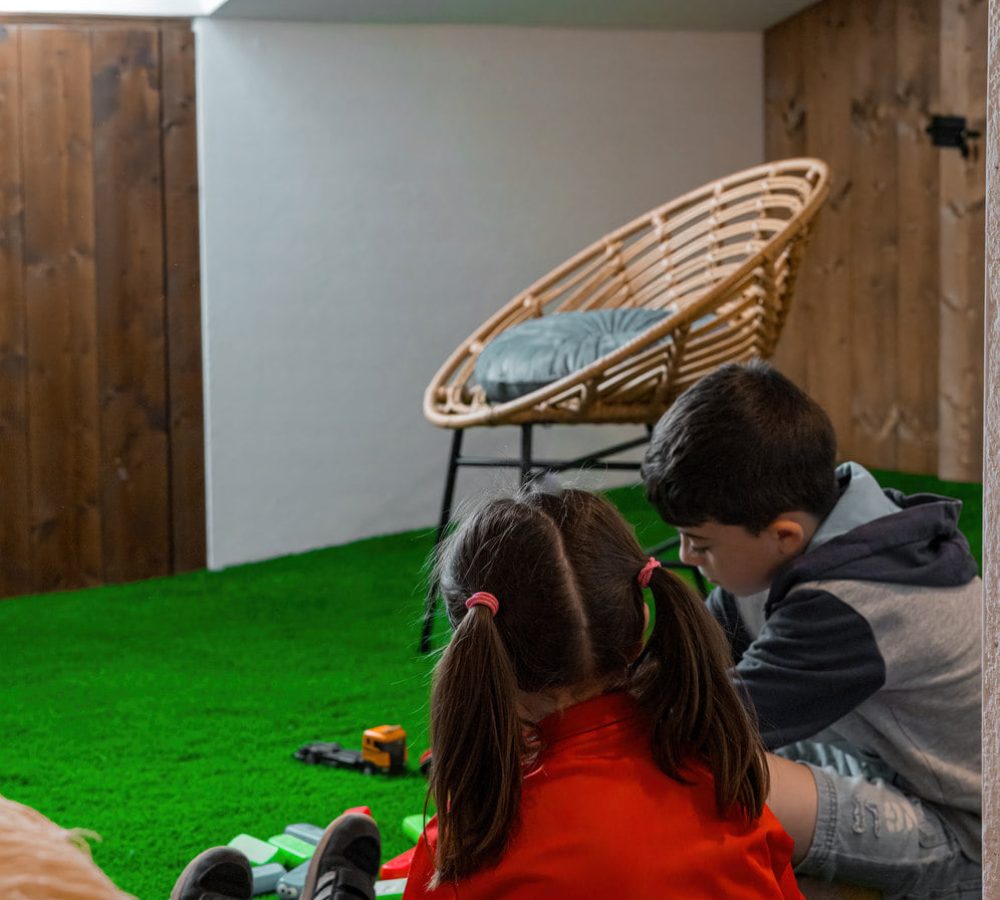 Niños jugando en una sala con césped artificial.