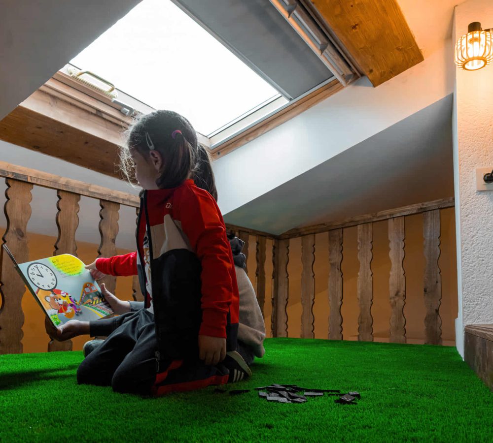 Niñas leyendo un libro en un espacio acogedor.