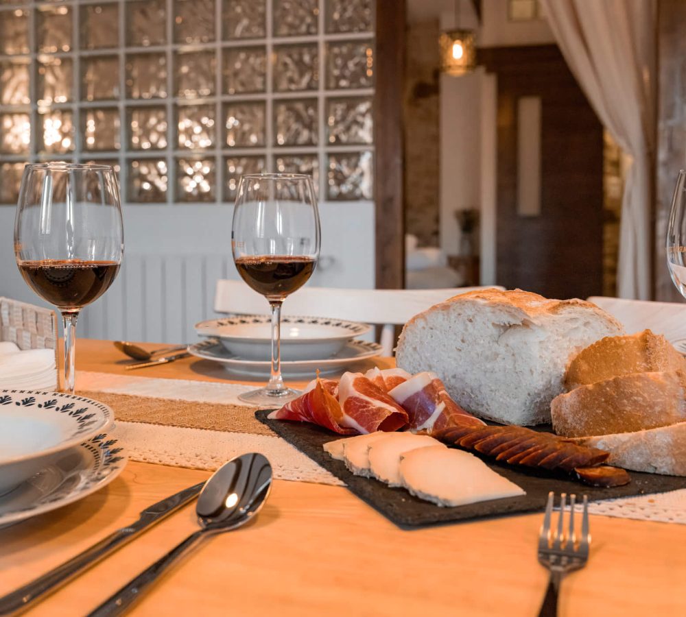 Mesa con vino, pan y embutidos variados.