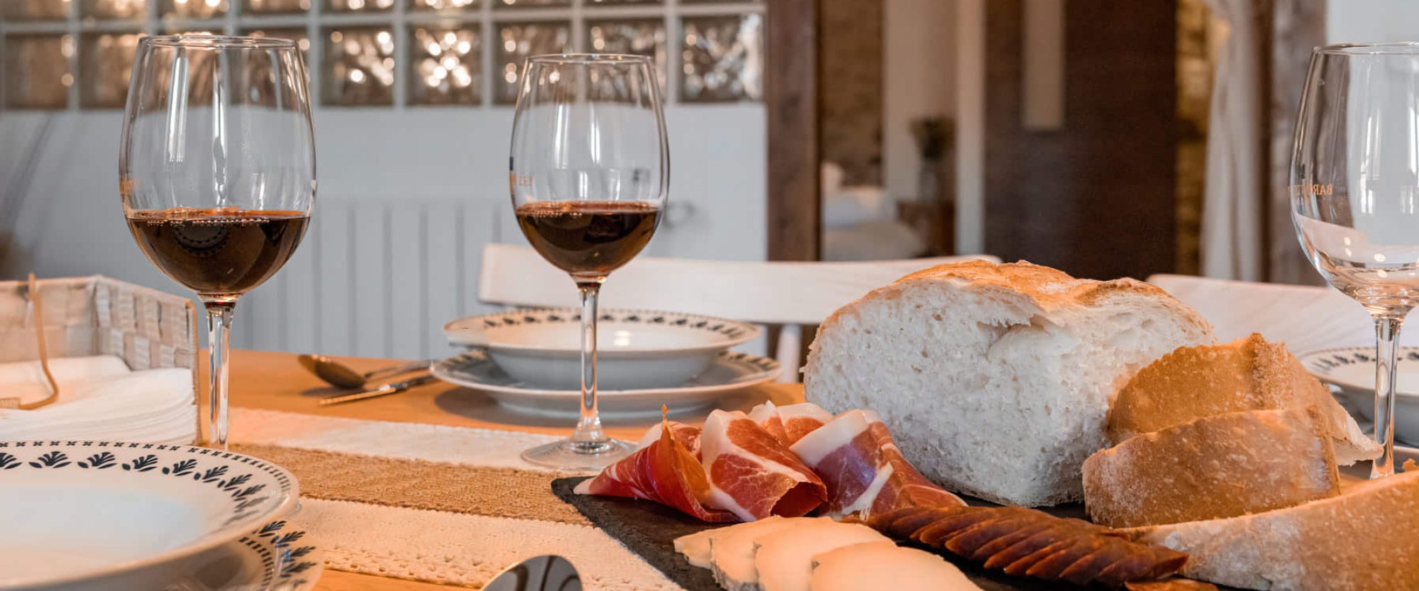 Mesa con vino, pan y embutidos variados.