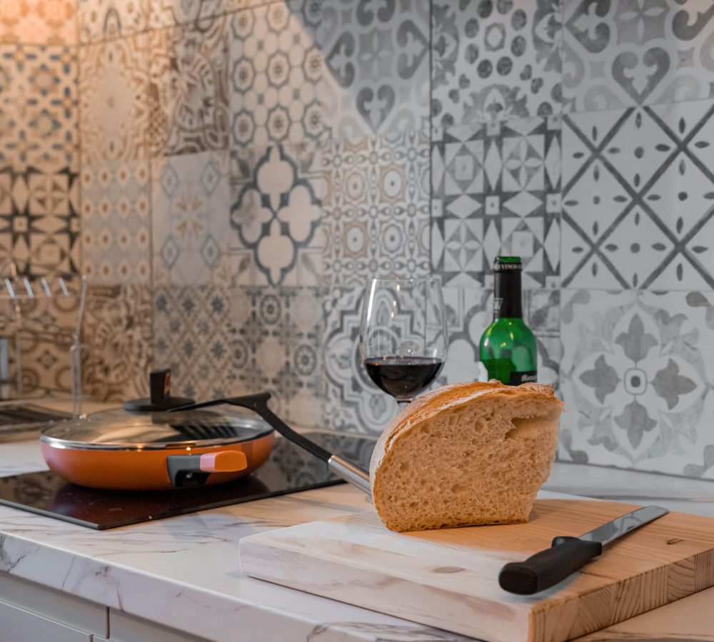 Cocina con pan, vino y utensilios en mesa.
