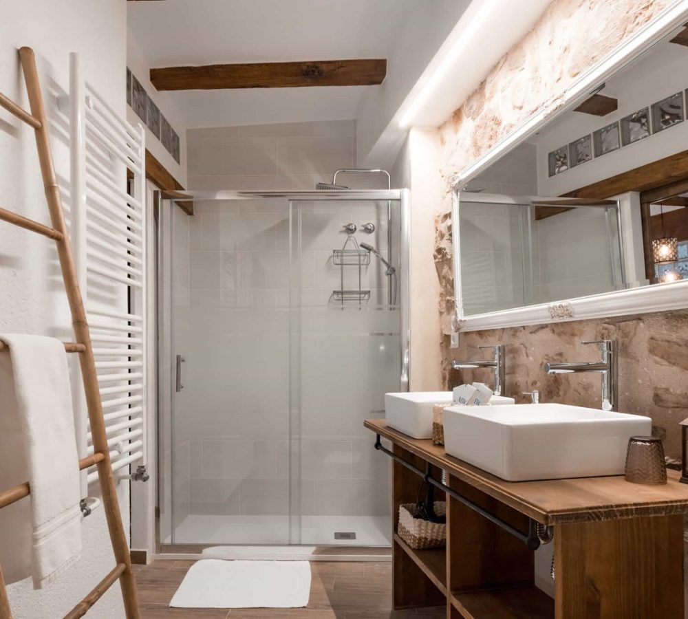 Baño moderno con ducha y lavabo doble.