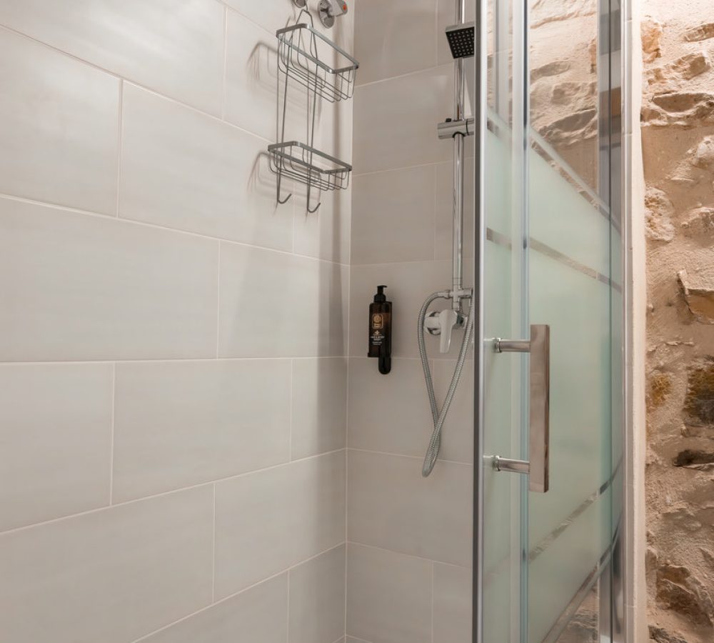 Baño con ducha moderna y paredes de azulejos