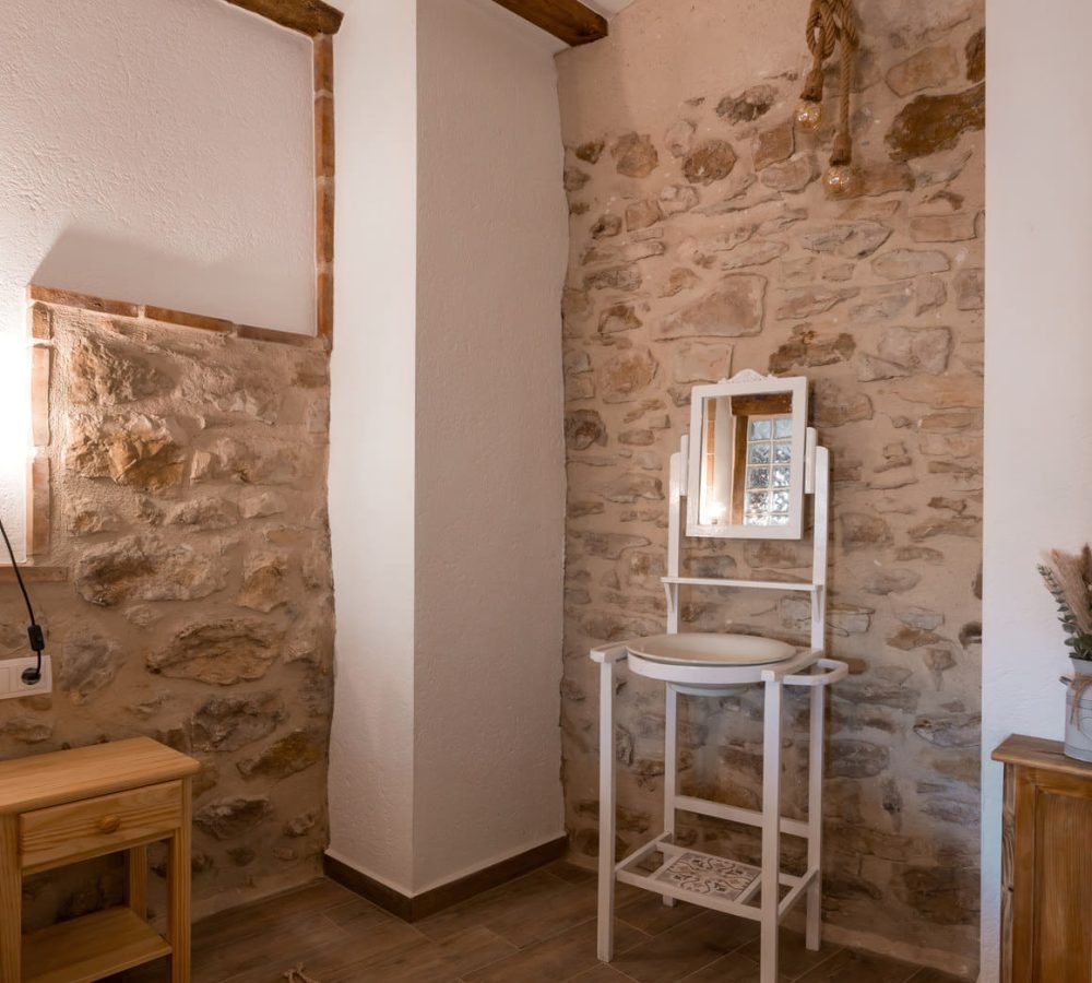 Esquina de habitación con espejo y piedra vista.