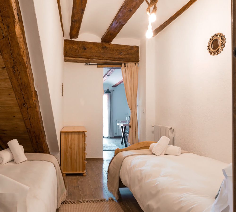 Habitación luminosa con techos de madera y camas.