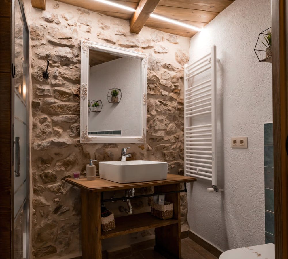 Baño con decoración rústica y lavabo moderno.