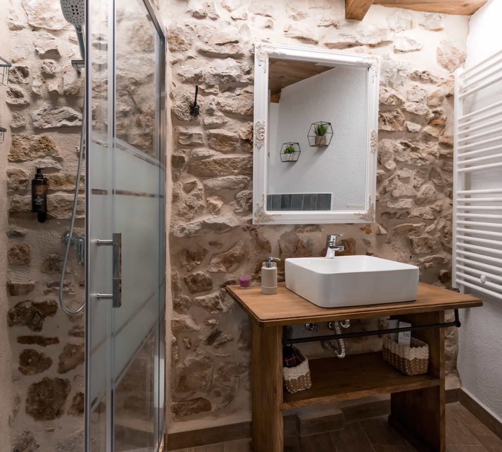 Baño moderno con paredes de piedra y arquitecturas de madera.