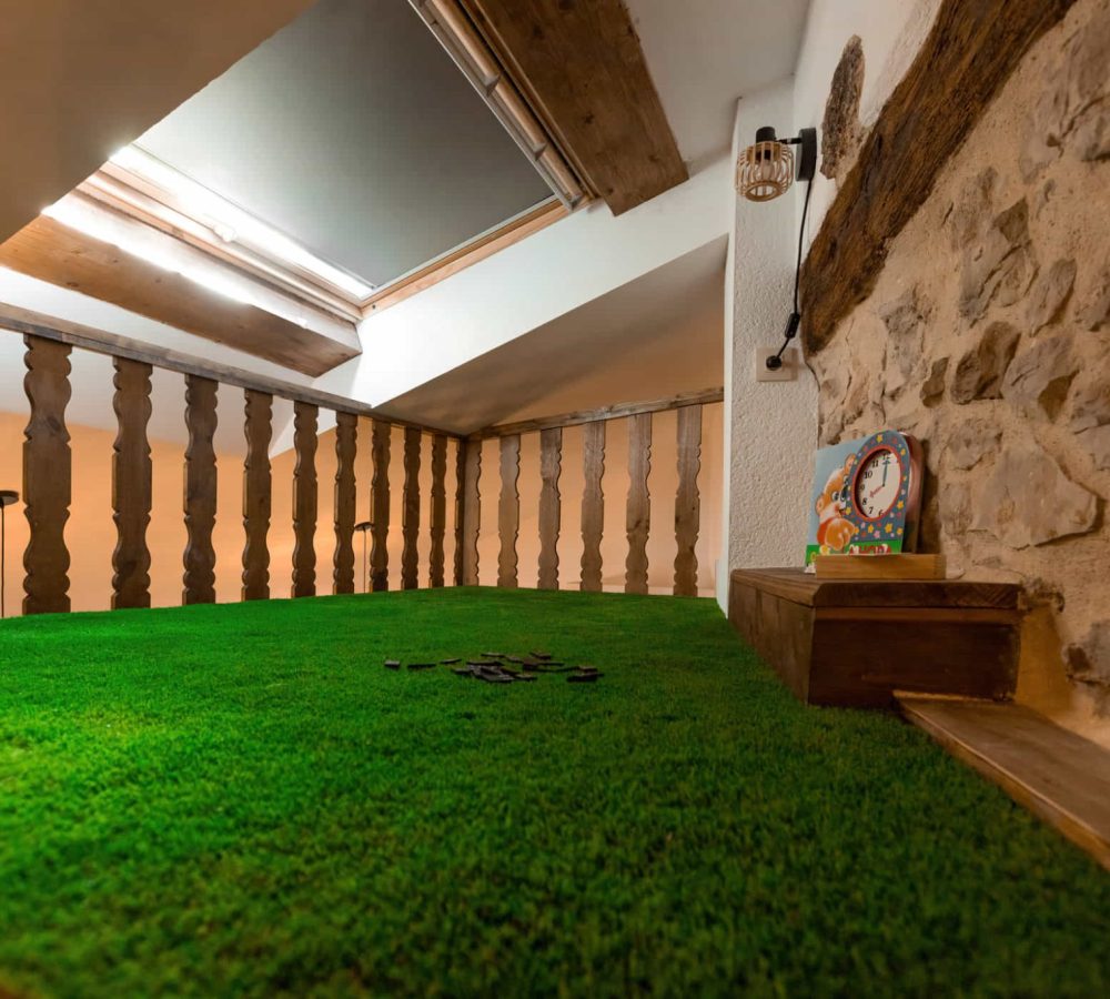 Espacio interior con césped artificial y barandilla.