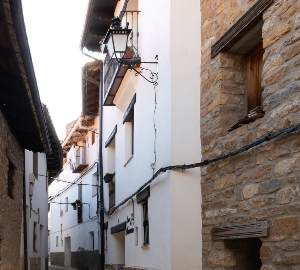 Calle empedrada entre casas de piedra y blancas.